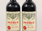 two bottles of red wine sitting next to each other on a white surface