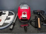 a red vacuum that is sitting on a table next to other items
