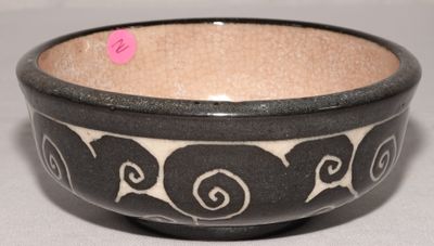 un bol noir et blanc posé sur une table, sur lequel est collé un autocollant rose