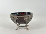 an antique silver plate with a red glass bowl on a stand