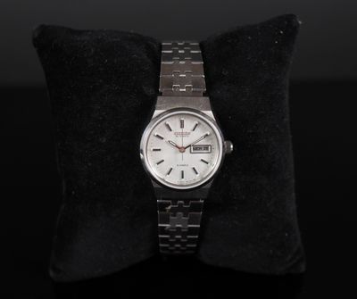 a close up of a watch sitting on a pillow on a black surface