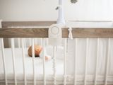 a baby laying in a crib next to a phone