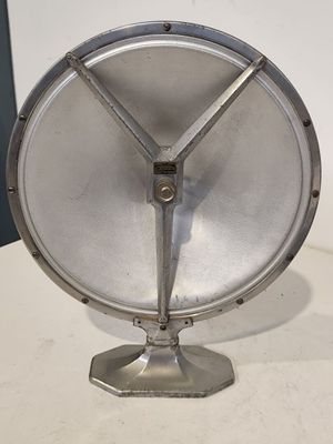 un objet métallique argenté posé sur une table, sur fond blanc