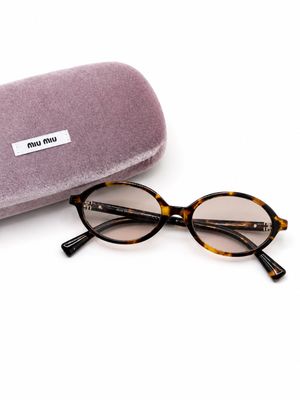 des lunettes de soleil et leur étui posés sur une surface blanche, sur fond blanc