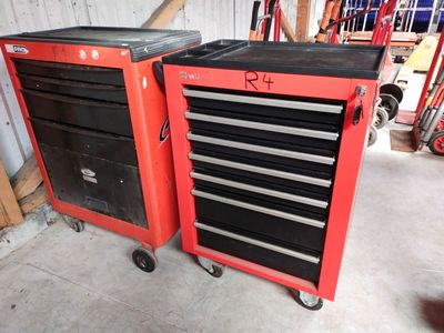 une paire d'armoires à outils rouges avec des tiroirs noirs et des roulettes, dans un garage