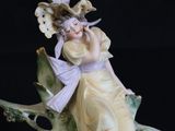 a figurine of a woman sitting on a tree branch
