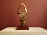 a gold sculpture on a table with a red wall in the background
