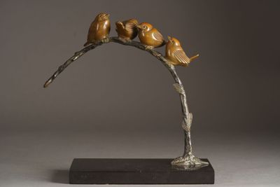 bronze sculpture of birds perched on a branch on a gray background