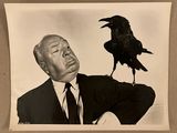 photographie en noir et blanc d'un homme en costume avec un corbeau sur l'épaule