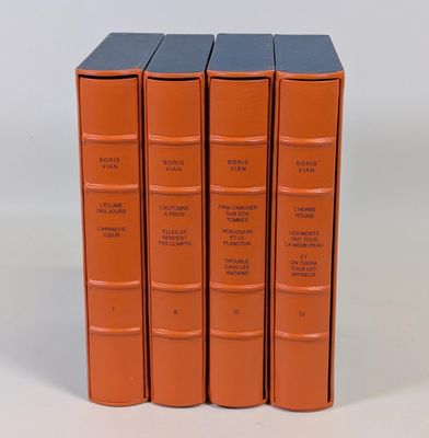 trois livres orange empilés les uns sur les autres sur une surface blanche