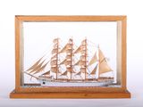 wooden model of a ship in a glass case on a white background