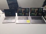 three laptops sitting on a white table with a black chair in the background