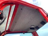 a close up of a red truck door with a steering wheel