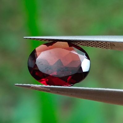 un gros plan d'une pierre rouge tenue par une pince