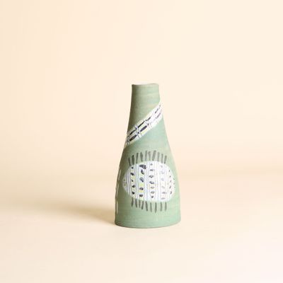 un vase vert orné d'un motif sur un fond blanc