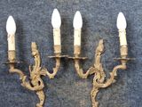 two antique brass wall sconces with white candles on them
