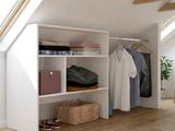 une armoire contenant des vêtements, sur laquelle sont posés d'autres vêtements, dans un loft