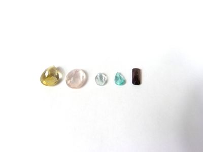 trois pierres de couleurs différentes sont disposées en ligne sur une surface blanche