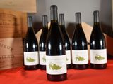 six bottles of red wine are lined up on a table