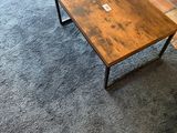 une petite table en bois sur laquelle est posé un ordinateur portable, dans un salon