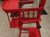 a red high chair with a cushion on it in a store
