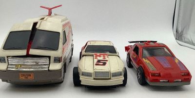 trois voitures jouets assises l'une à côté de l'autre sur une table