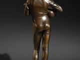 a bronze statue of a man holding a ball on a pedestal