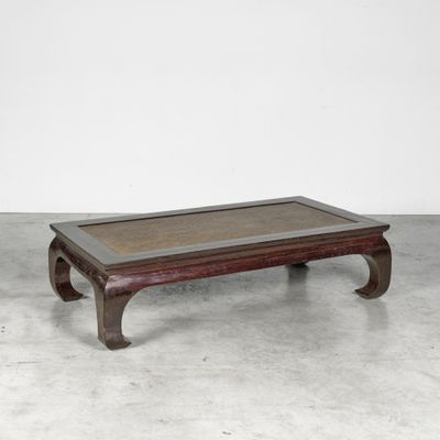 an old wooden coffee table with a glass top on a concrete floor