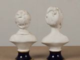 two white busts sitting on top of a wooden table