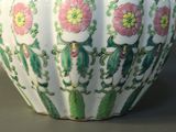 a white vase with green and pink flowers on it