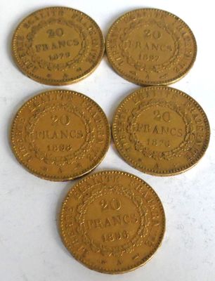 five gold coins sitting on top of each other on a white surface