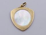 a close up of a gold pendant with a mother of pearl in the center