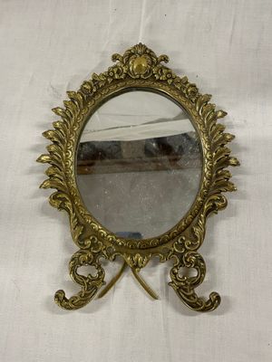 un miroir plaqué laiton posé sur une table blanche recouverte d'une nappe blanche