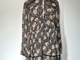 La robe est noire et blanche, avec des fleurs roses.