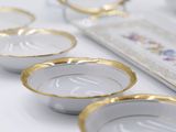 a white table with gold rims and white dishes on it