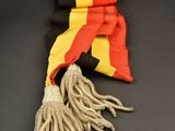 yellow, black and red scarf with tassels on a black surface