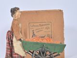 toy figurine of a woman pushing a wagon filled with carrots