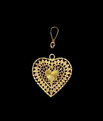 un pendentif en forme de cœur en or, orné de pois noirs et blancs