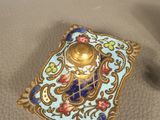 a small blue and gold object on a table next to a pair of scissors