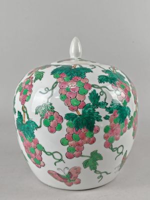 une image représentant un bocal en forme de pomme, blanc et rose, orné de raisins