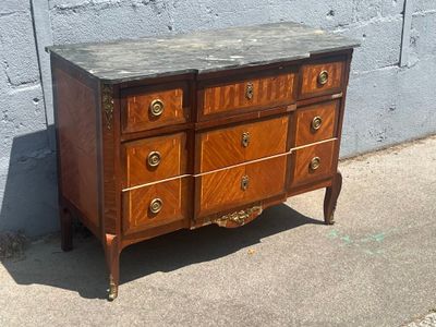 une commode en bois avec un plateau en marbre, posée sur le trottoir
