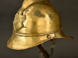 an old brass helmet on a clear stand against a black background