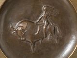 a bronze plate with a picture of a woman riding a bull