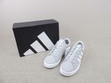 Les baskets adidas sont dans une boîte posée par terre.
