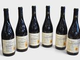 six bottles of wine are lined up in a row on a white surface