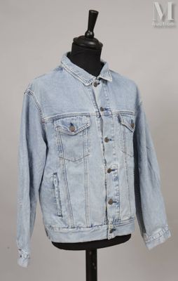 une veste en jean posée sur un socle de mannequin, dans une vitrine de mannequins