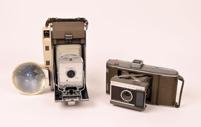 two old cameras sitting next to each other on a white surface