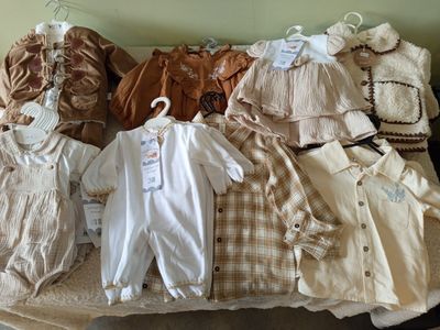 a lot of baby clothes on a bed in a room