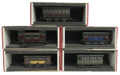 Six petits trains se trouvent dans une boîte posée sur une surface blanche.