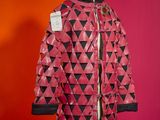 pink and black jacket on a mannequin stand against a red wall